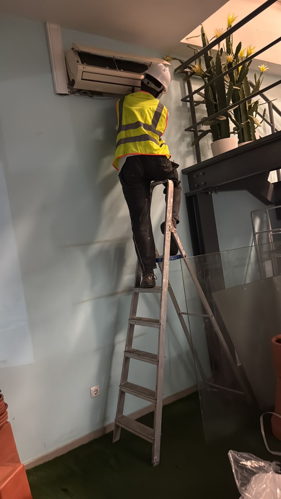 Técnico em escada a fazer manutenção de AC